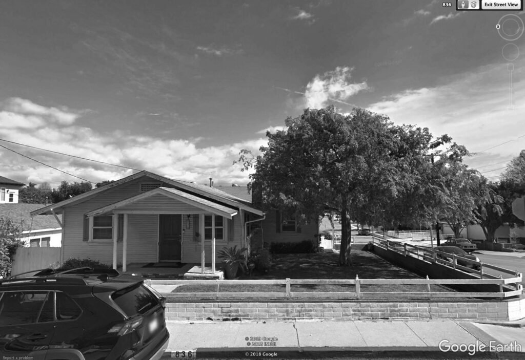 before image of the front of the property with a big tree on the side.