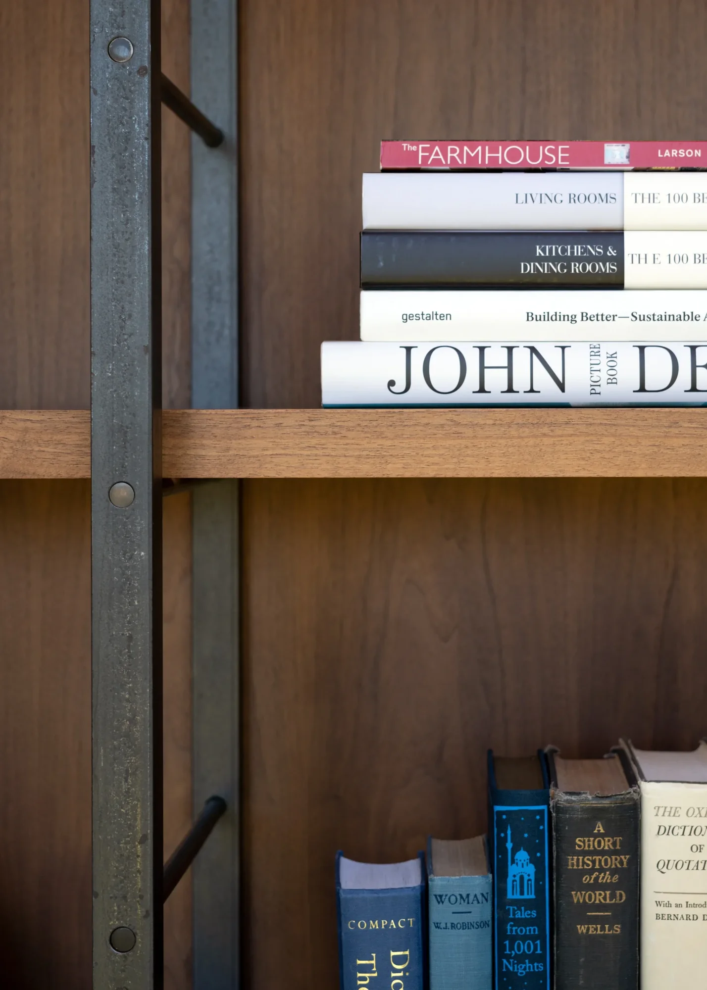 Wooden shelf with design and architecture books on industrial metal frame against warm wood paneling